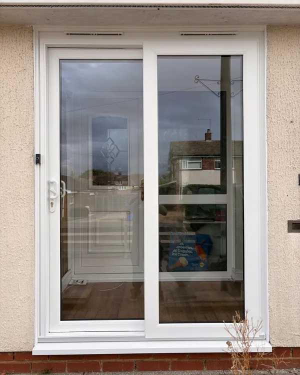 Two-pane white uPVC sliding patio door fitted in a rendered wall.