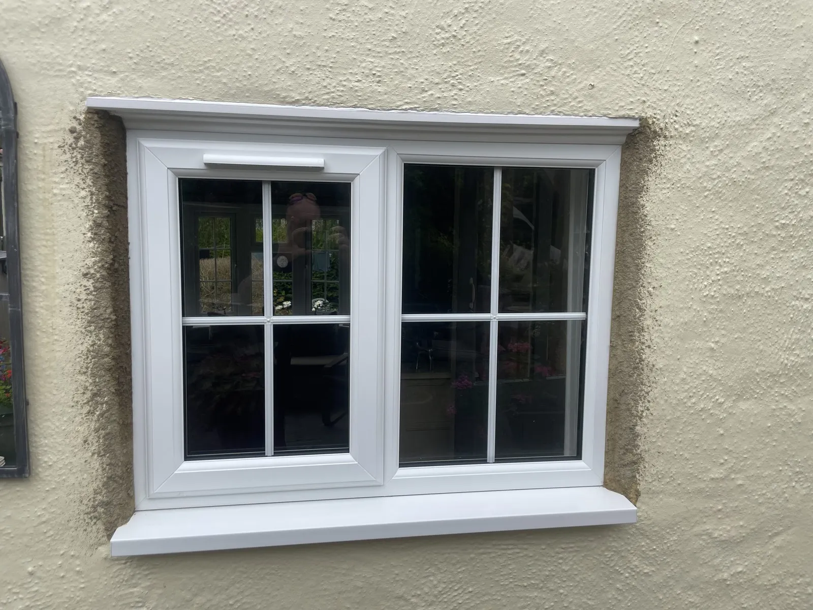 White uPVC casement window with Georgian bars and a deep sill, fitted in a cream rendered wall.
