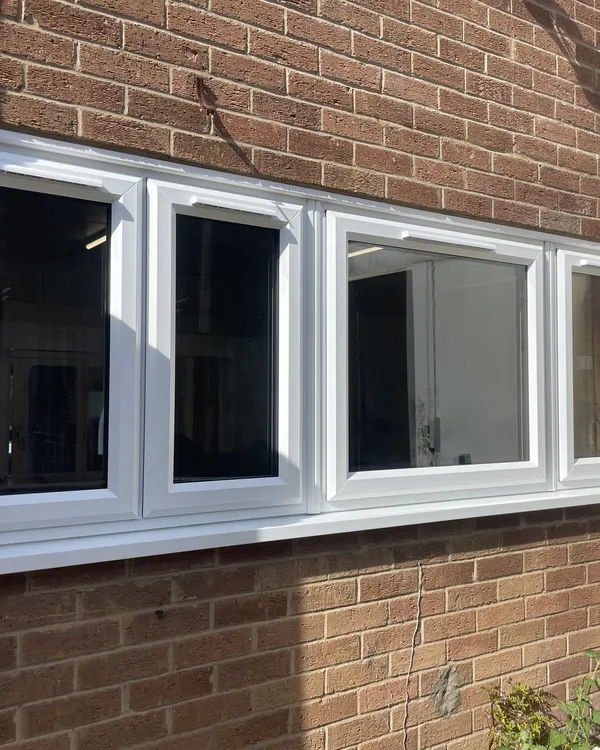 Long run of white uPVC casement windows fitted in the brick wall of a commercial building.