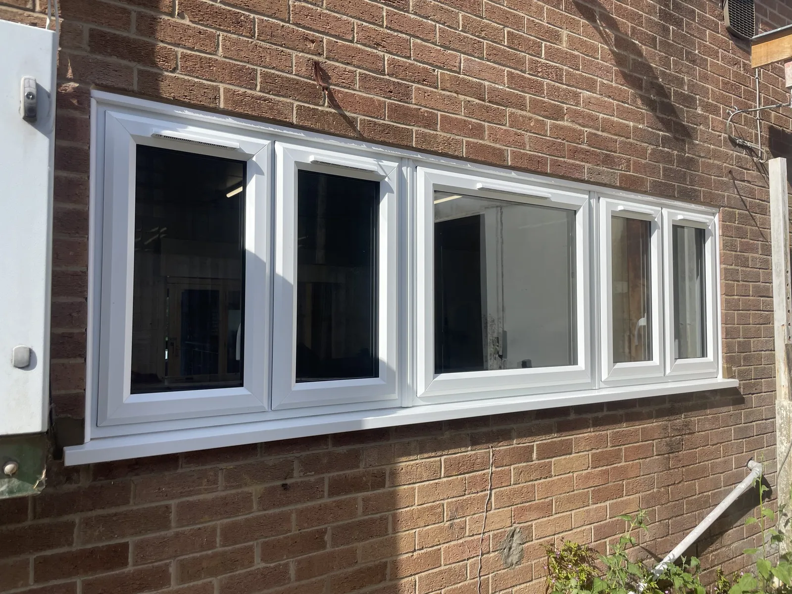 Long run of white uPVC casement windows fitted in the brick wall of a commercial building.