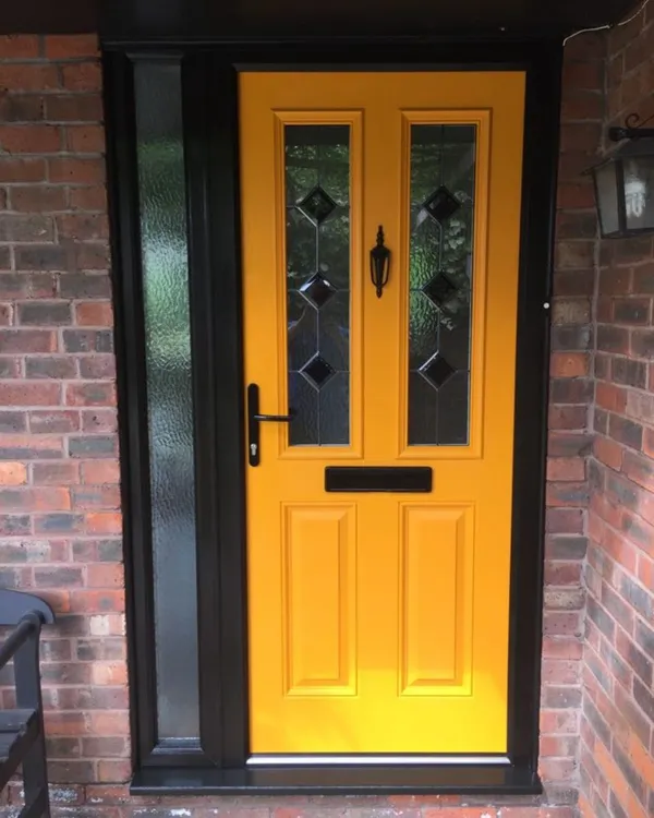 Bright yellow composite front door with diamond glass detail and black handle, fitted in a black frame with a glazed side panel.